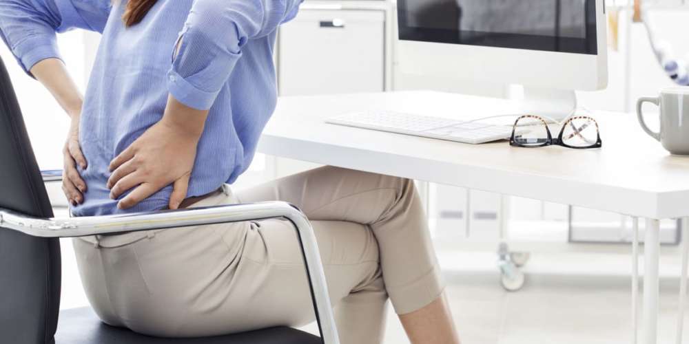 donna seduta con dolore alla schiena, dolore sciatica sindrome piriforme