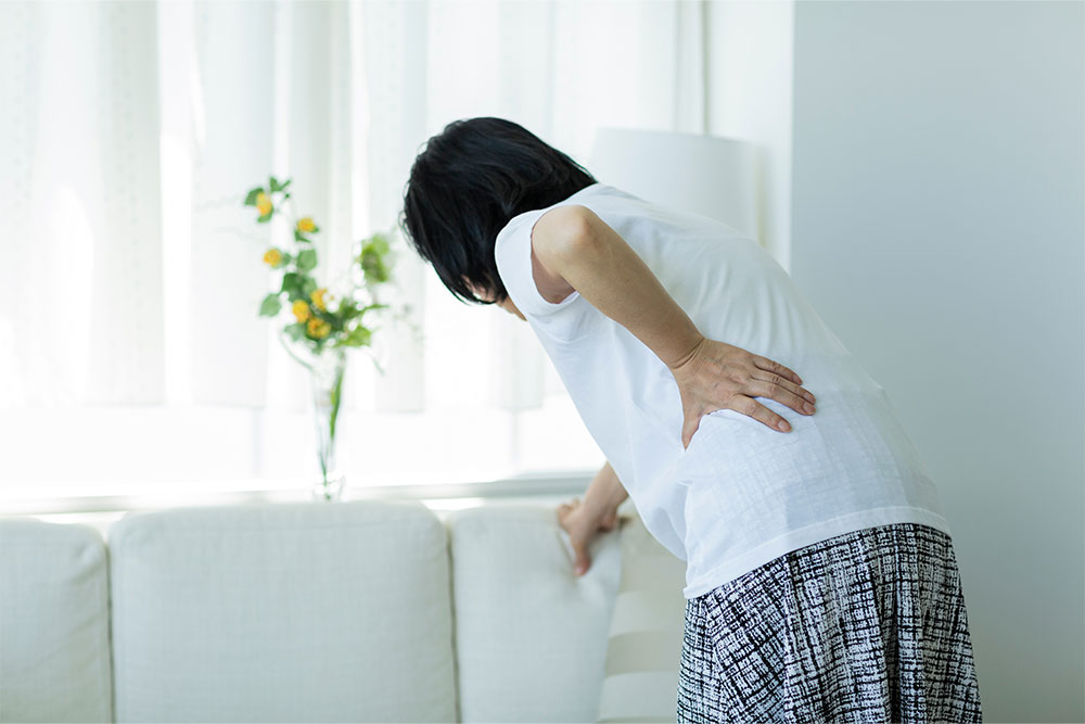 donna con mal di schiena si regge al divano